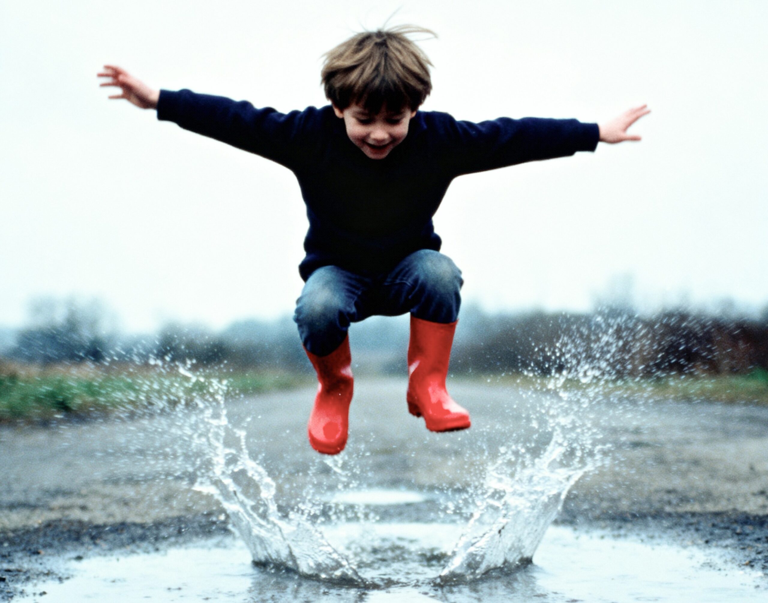 Boy jumping in a puddle