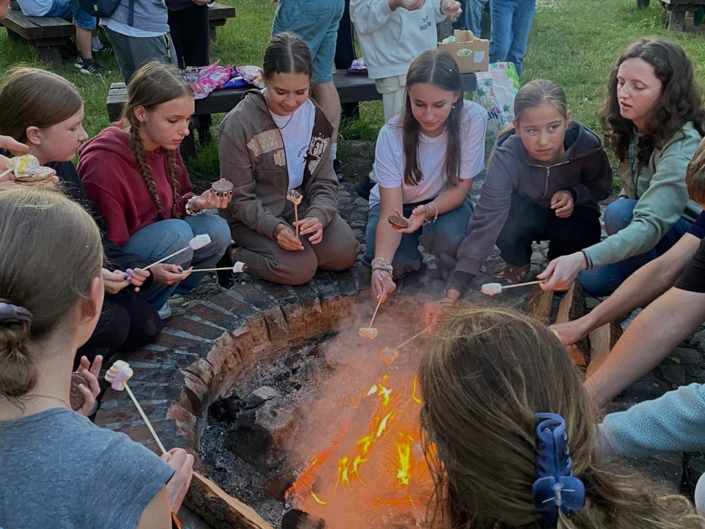 children round a fire pit roasting marshmallows