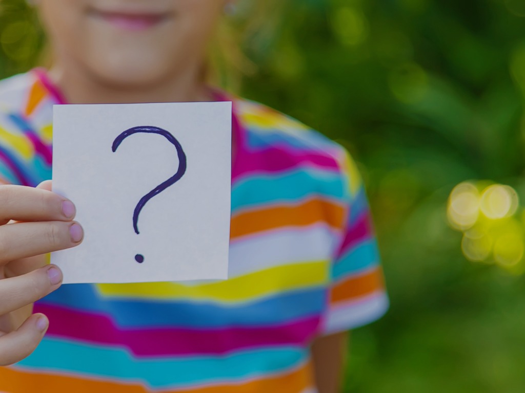 child holding a card which has a question mark on it