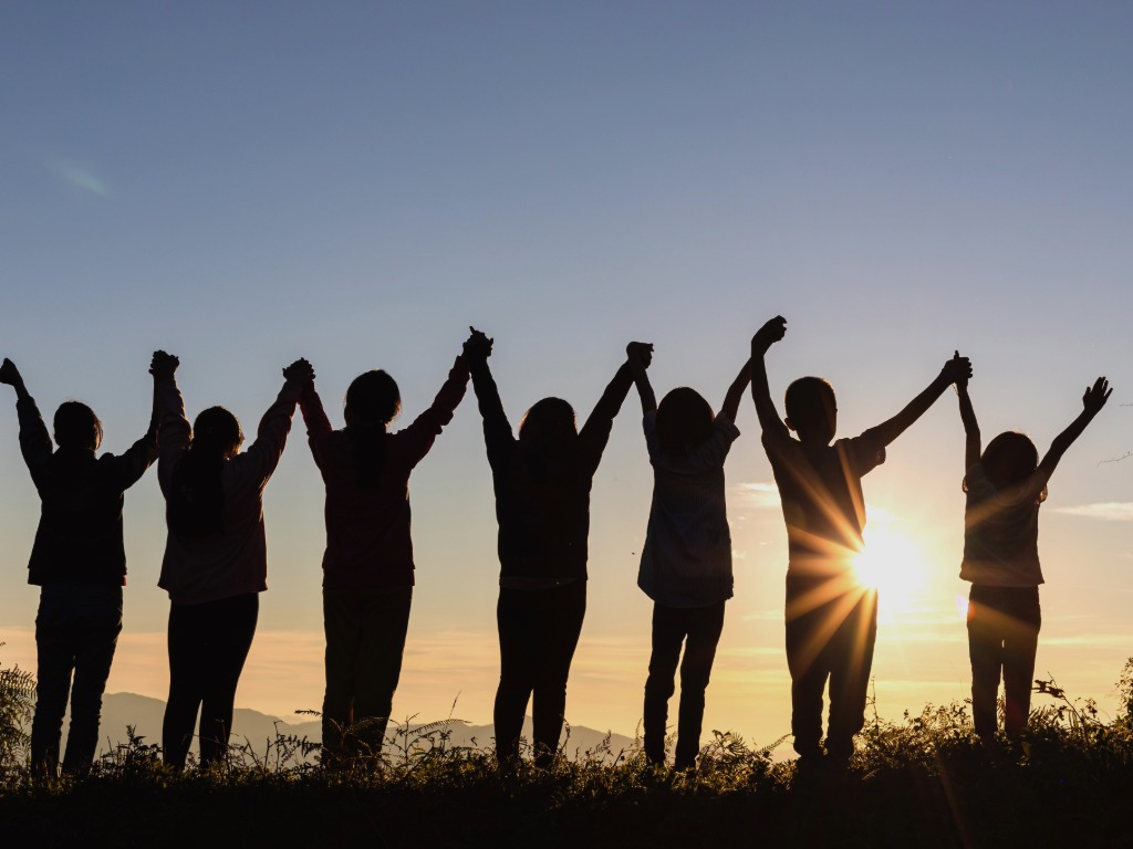 silhouette of children with arms raised in the air