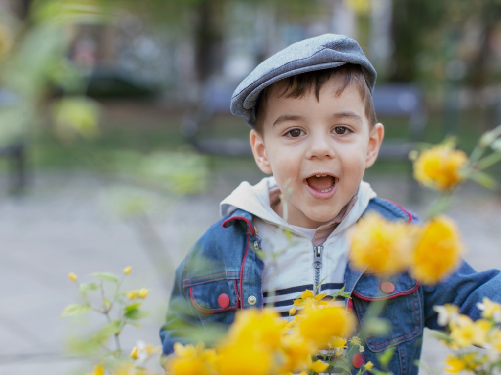 child smiling with flowers around