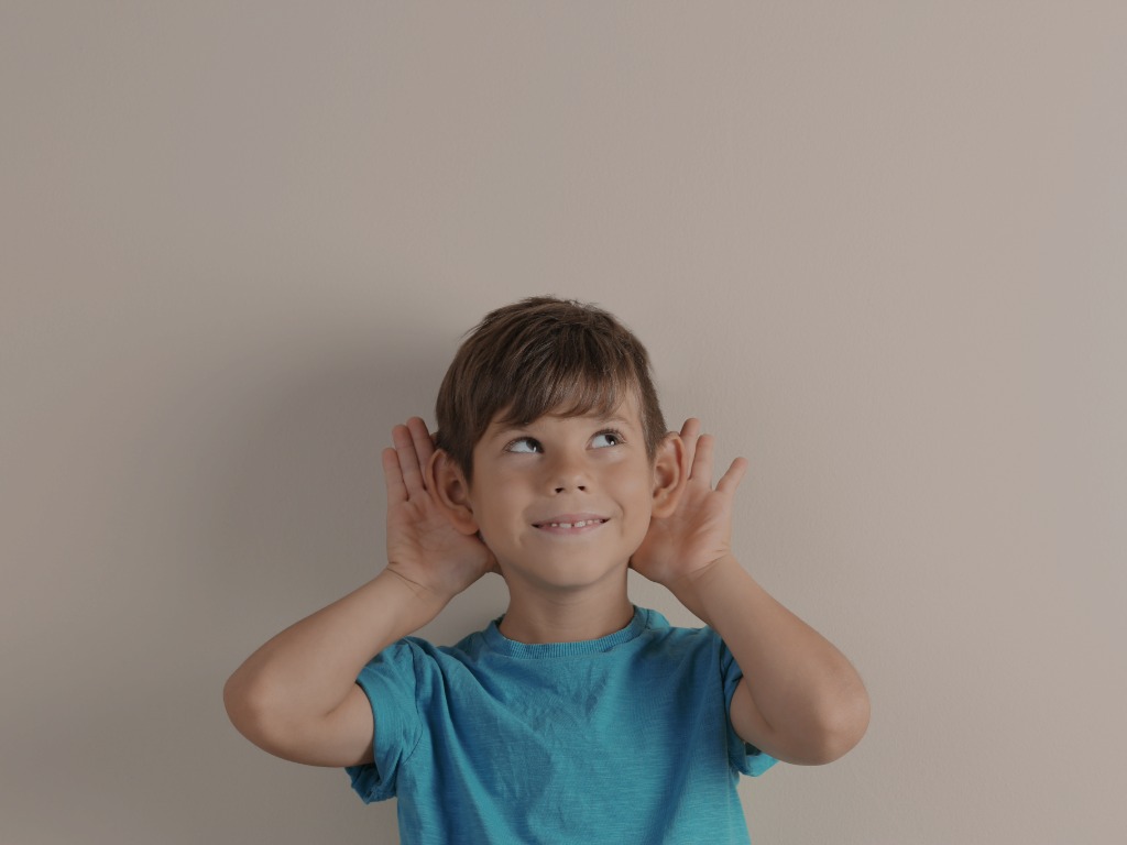 Child with his hands up at his ears, showing that he is listening