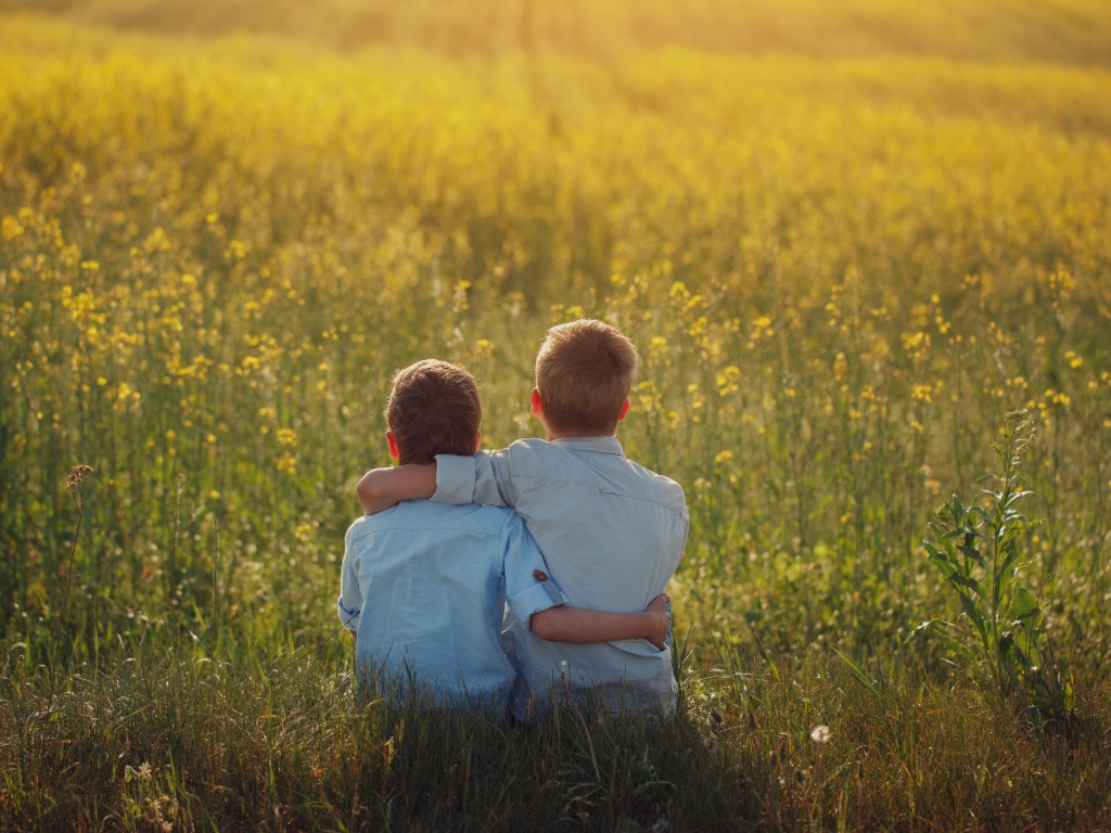 2 boys sitting with arm around neck