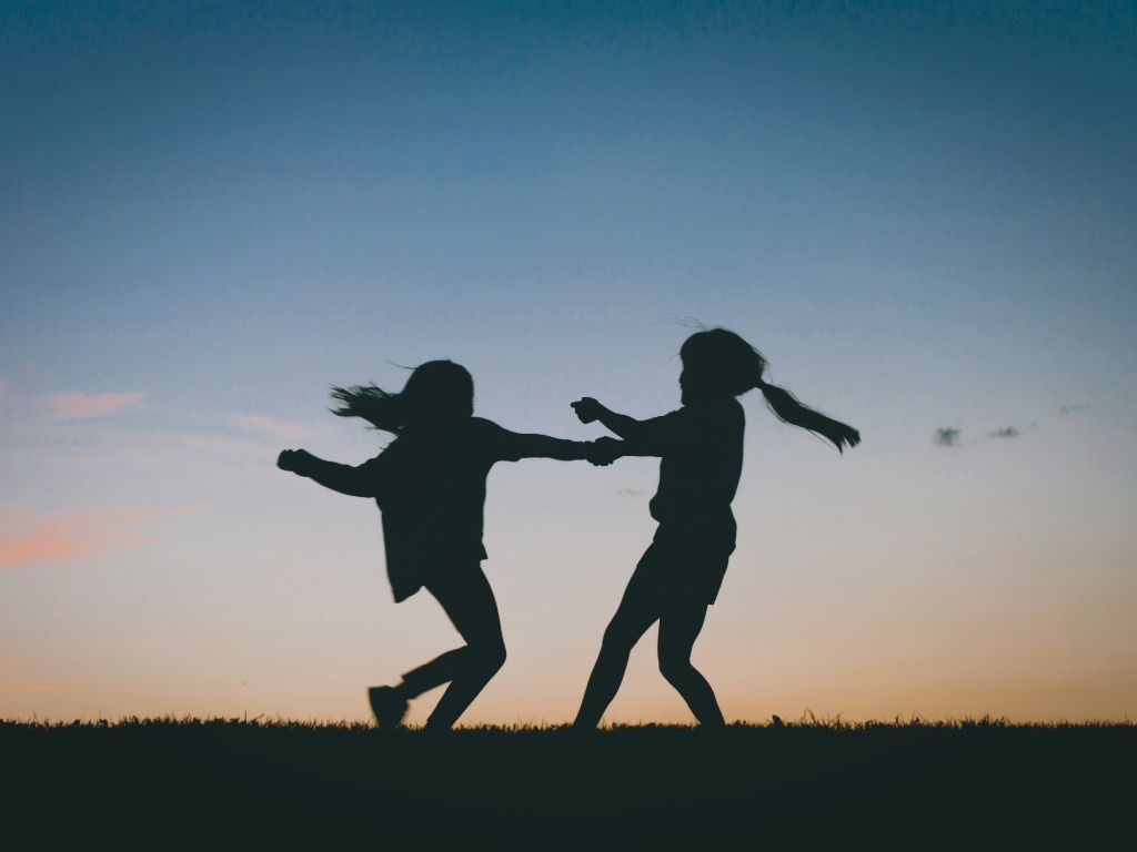 two girls playing, with a sunset background