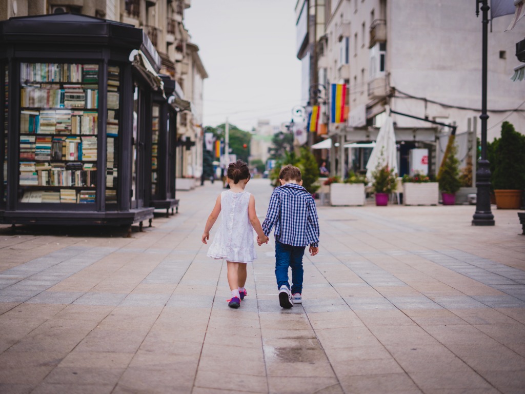 Two children walking hand in hand through a street in Romania