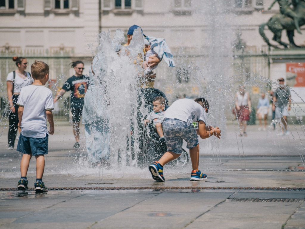 boys playing in a water fountain in Italy